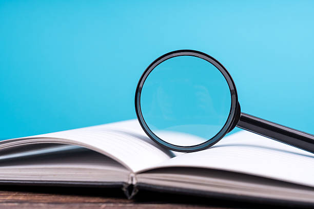 istock Magnifying glass on an open book on a wooden background 2227988262
