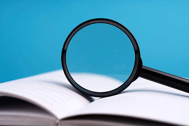 istock Magnifying glass on an open book on a wooden background 2227989006