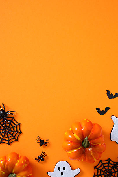istock Halloween flat lay on orange background featuring pumpkins, ghosts, spiders, bats, and webs arranged around empty center 2227990962