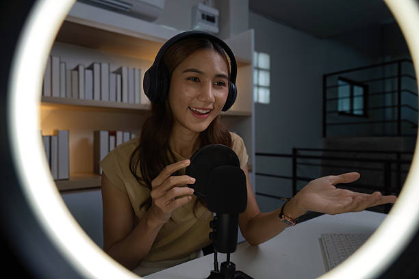 istock Engaging Online Presence. Young woman smiling while interacting with her audience through a microphone. 2227991059