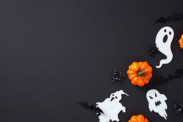 istock Halloween corner layout with bright pumpkins, ghost cutouts, bats, and spiders on black background. Empty space for text, festive and spooky mood. 2227991611
