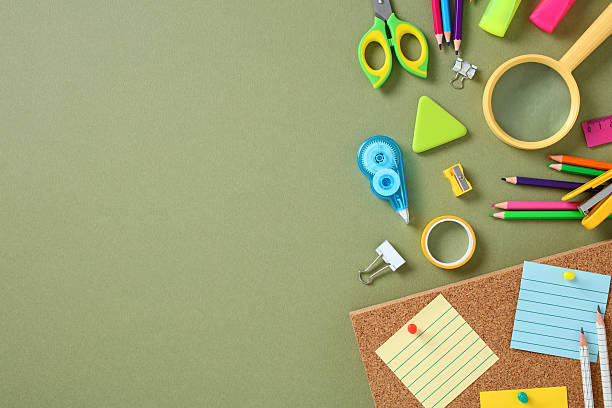 istock School stationery on green background: colored pencils, magnifying glass, ruler, scissors, eraser, sticky notes, and push pins 2227992002