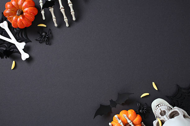 istock Spooky Halloween flat lay composition with pumpkins, skull, skeletal hands, bones, worms, bats, and spiders on dark background. 2227992227