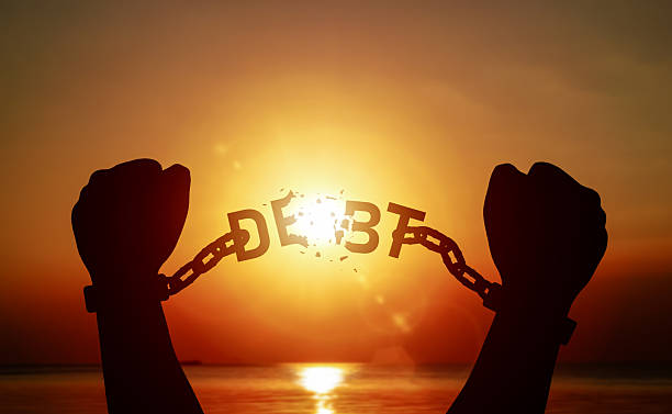 istock Silhouette of raised hand pulling a chain with word DEBT on until it breaks. Concept of debt relief, freedom from debt. 2227999933