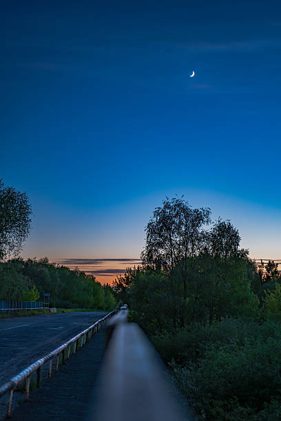 Twilight Road with Crescent Moon and Trees in Rural Belarus