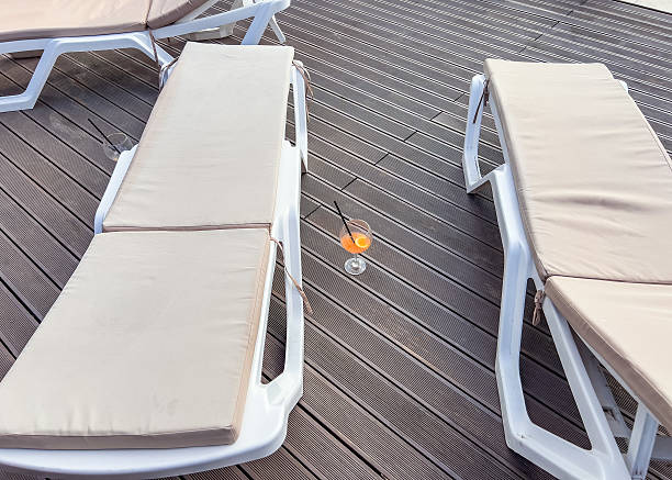 istock Relaxation area by the pool featuring several sun loungers with light-colored cushions on a wooden deck. A peaceful and stylish outdoor setting designed for comfort and leisure, perfect for summer vibes and vacation themes. 2228006931