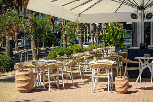 istock Cozy Roadside Cafe with Wicker Seating and Palm Tree Street View 2228007625