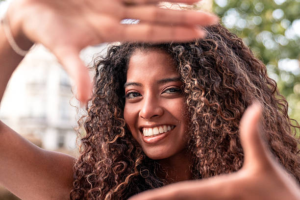 istock Young woman framing her face with hands and smiling 2228014433