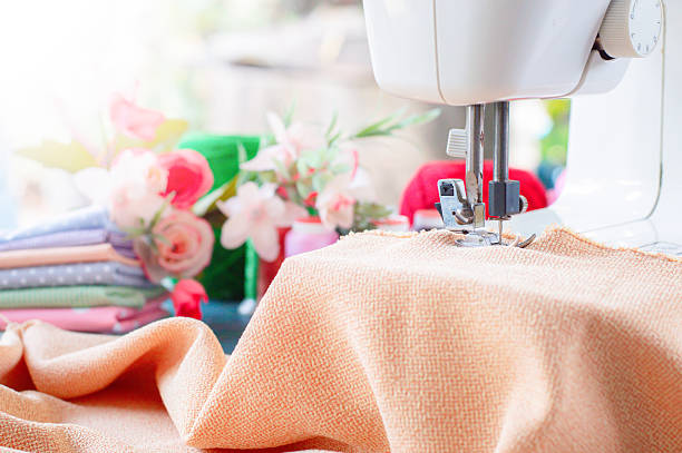 Sewing machine working with brown fabric, sewing accessories on the table, stitch new clothing.
