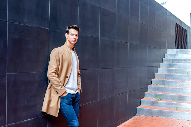 istock Stylish man leaning on wall with modern stairs 2228022683