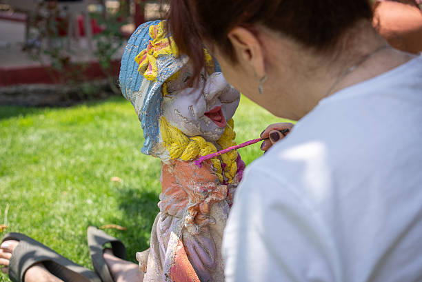 Middle-aged woman painting decorative statue in backyard