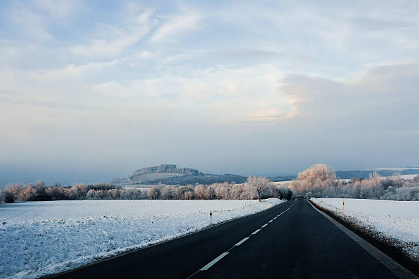 White trees covered with fluffy hoarfrost against a bright blue sky on a cold winter day. Rocky cliffs in Bavaria, Germany. Winter nature, frost, cold weather, scenic natural environment.