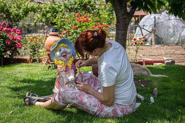 Middle-aged woman painting decorative statue in backyard