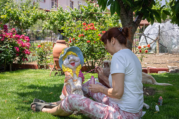 Middle-aged woman painting decorative statue in backyard