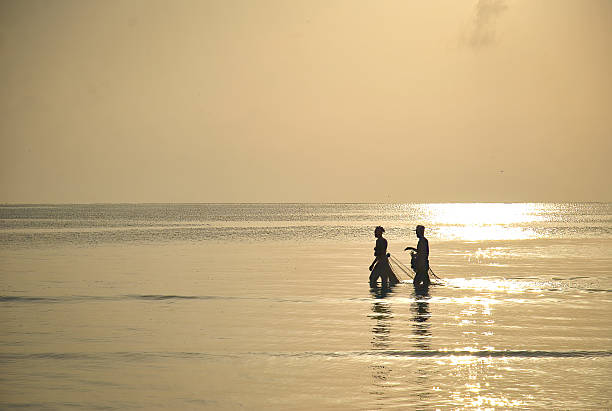 istock Two people walking through shallow sea water 2228030104
