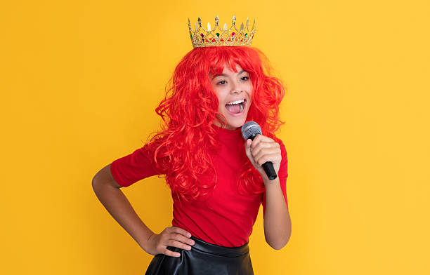istock happy child in crown with microphone on yellow background 2228031616