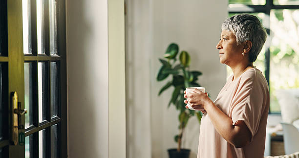 istock Thinking, senior woman and coffee at window for past memory, nostalgia and morning routine. Lonely, elderly person and reflection with beverage, retirement decision and daydreaming with view at house 2228035199