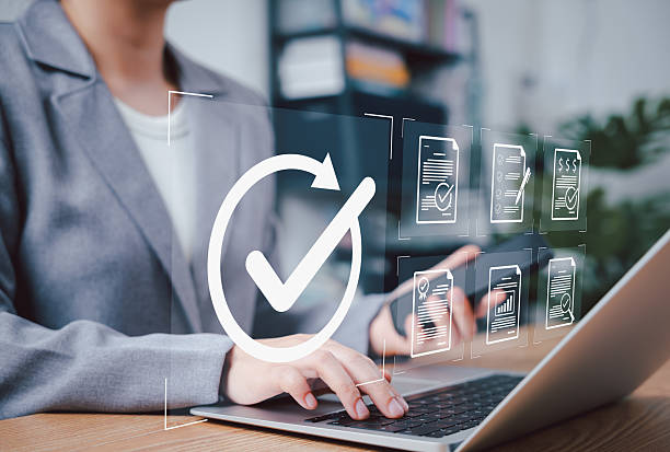 istock Document Approval and Quality Assurance Process Concept. A professional working on laptop with icons of documents and check mark, symbolizing document validation, compliance, and approval workflow. 2228037364