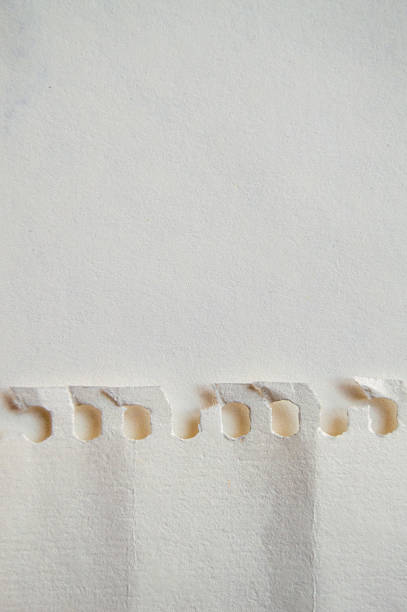 Vertical plain white  blank empty crumpled wrinkled weathered old crinkled paper with uneven full frame wrinkles page of spiral art sketch book notepad with copy space and perforated at left edge from holes puncher placed on another plain white paper sheet.