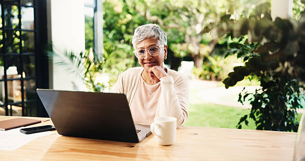 istock Thinking, remote work and mature woman with laptop for planning lesson or course idea. Happy freelancer, computer and solution in home backyard for education insight or teacher reading good essay 2228044466