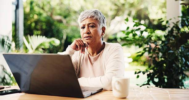istock Thinking, freelancer and mature woman with laptop for reading, planning lesson or course idea. Remote work, computer or problem solving with thoughts in home backyard for education with serious tutor 2228044467