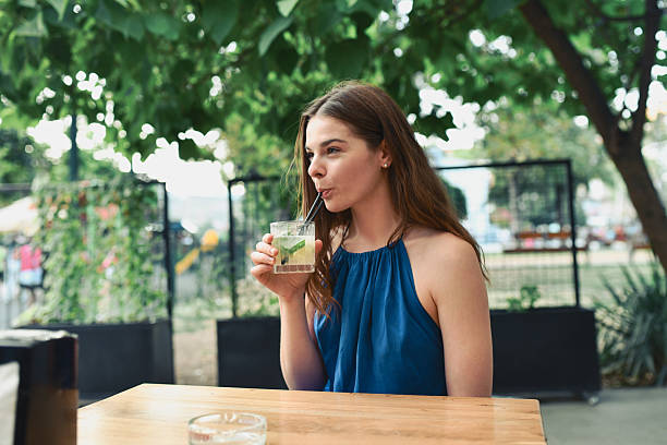 istock Stylish Woman Enjoying Refreshing Cocktail While Relaxing At Trendy Outdoor Bar 2228045607
