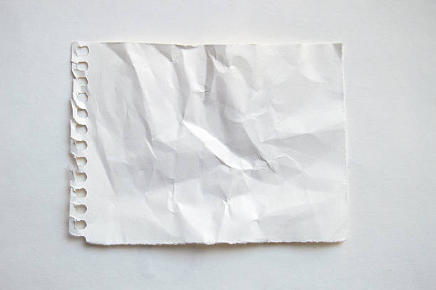 Horizontal plain white  blank empty crumpled wrinkled weathered old crinkled paper with uneven full frame wrinkles page of spiral art sketch book notepad with copy space and perforated at left edge from holes puncher placed on another plain white paper sheet.