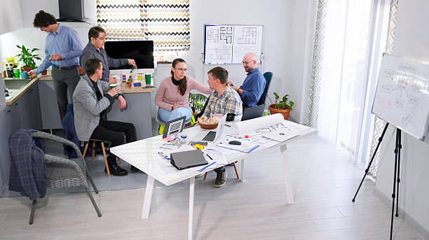 istock Colleagues from the architectural bureau arranged a coffee break in the conference room. A group of people are sitting at a table in the cozy kitchen 2228051126