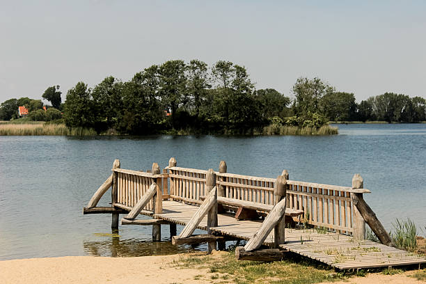 istock Rustic Wooden Dock with Fence Overlooking a Tranquil Lake Surrounded by Trees 2228053390