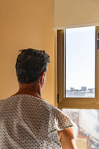 istock Patient looking out bright hospital window at cityscape 2228053868