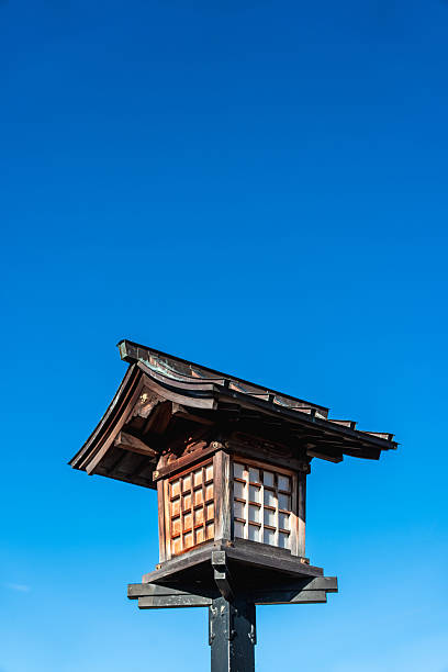 Traditional japanese wooden lantern standing against a clear blue sky