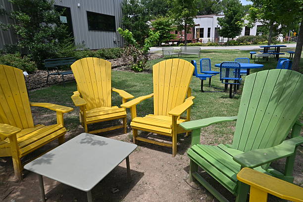 Outdoor seating area with wicker and metal furniture on a lush green lawn. The scene includes trees and a pathway in the background, suggesting a peaceful garden setting