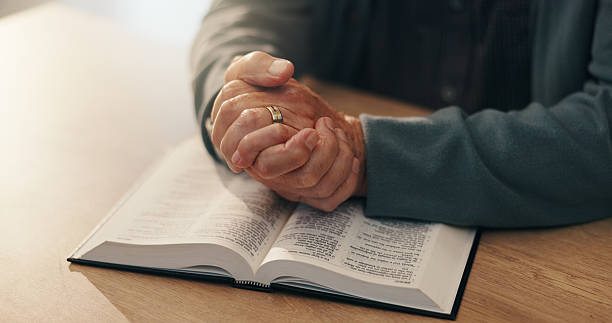 istock Hands, bible study and religion in home, retirement and reading scripture for marriage, info and spiritual knowledge. Elderly person, book and faith with story, chapter or gospel for God at apartment 2228065346