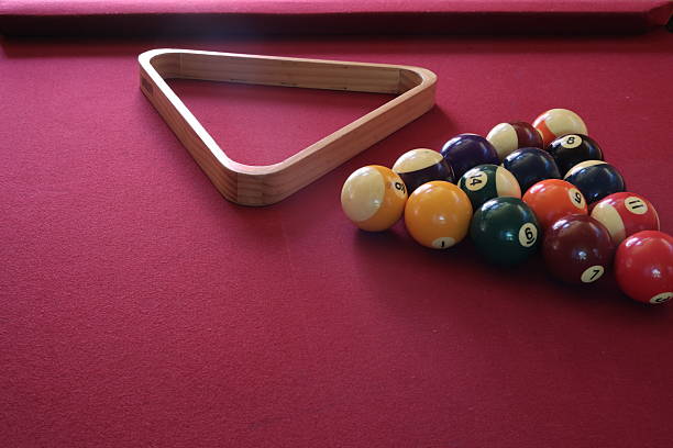 istock Billiard balls and a wooden triangle rack positioned on a vivid ruby red pool table, ready for the game. 2228065751