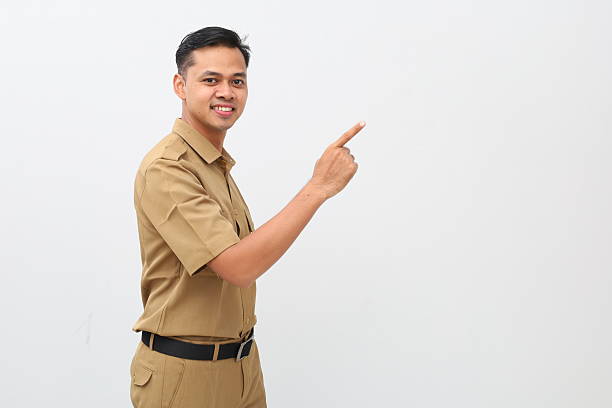 istock Side view of Indonesian civil servant man standing while pointing beside him 2228066596