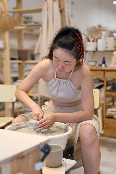 istock Young artisan shaping clay on pottery wheel in workshop 2228067900