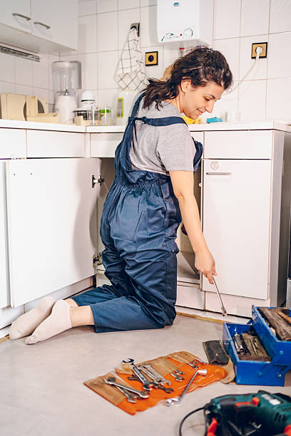 istock Female plumber repairing pipes in kitchen 2228078028