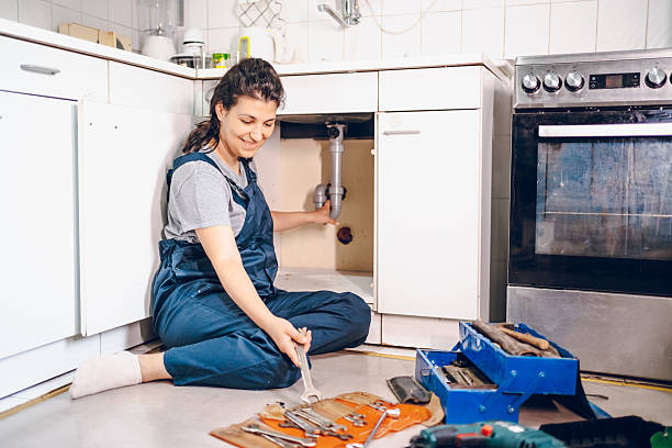 istock Female plumber repairing pipes in kitchen 2228078108