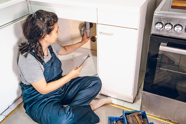 istock Female plumber repairing pipes in kitchen 2228079089
