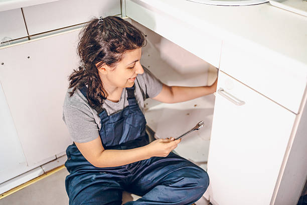 istock Female plumber repairing pipes in kitchen 2228079151
