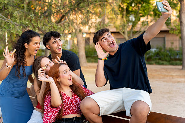 istock Group of cheerful students taking a selfie while eating snacks in a park 2228085608