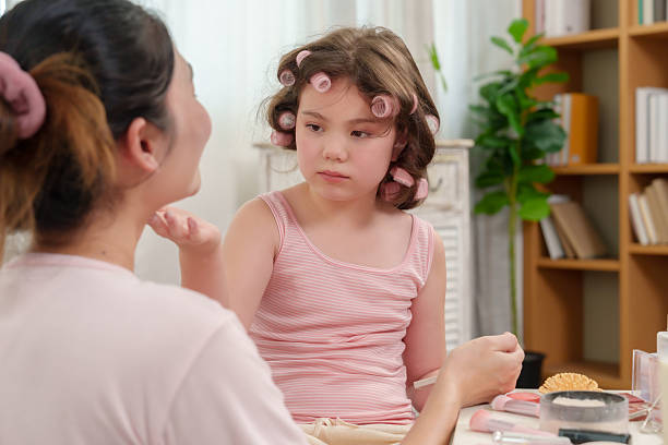 istock Asian daughter playfully holding powder puff while interacting with smiling mother during beauty session, strong emotional connection, nurturing trust and affection between family members at home. 2228086778