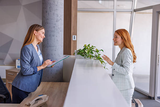 istock Businesswoman checking in at hotel reception talking to receptionist 2228093619