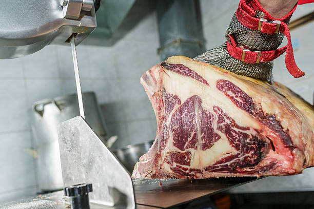 istock Butcher Cutting Dry Aged Marbled Ribeye Steak with Saw on Stainless Table in Meat Processing Room 2228097571