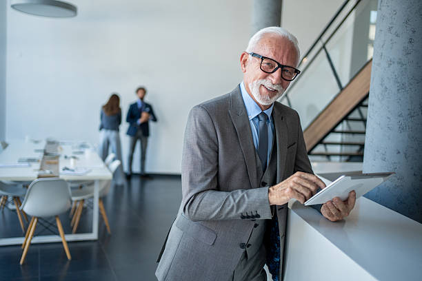 istock Senior businessman smiling and using digital tablet in modern office 2228111010
