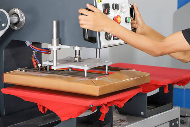 istock press printing on colored t-shirts, press for printing images on fabric. Large industrial textile printing machine, when printing textiles for male workers 2228113003