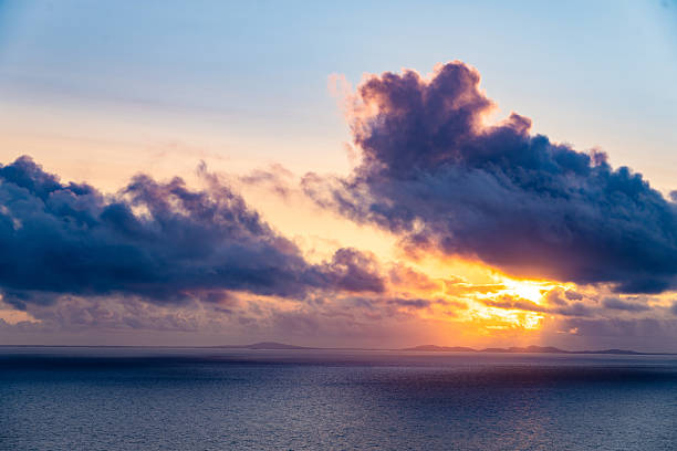 Breathtaking sunset over a tranquil ocean, with golden light piercing through dramatic clouds