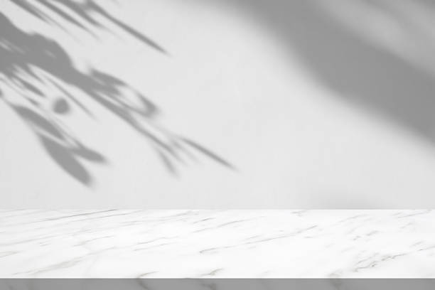 istock Marble table with tree shadow drop on white wall background for mockup product display 2228116161