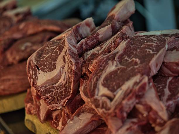 Variety of fresh meat at the butcher's shop and unrecognizable man grabbing a piece - Raw food