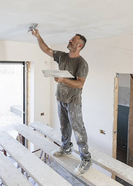 istock Man working standing on scaffoldings, use trowel and hawk to plaster ceiling, construction 2228121077